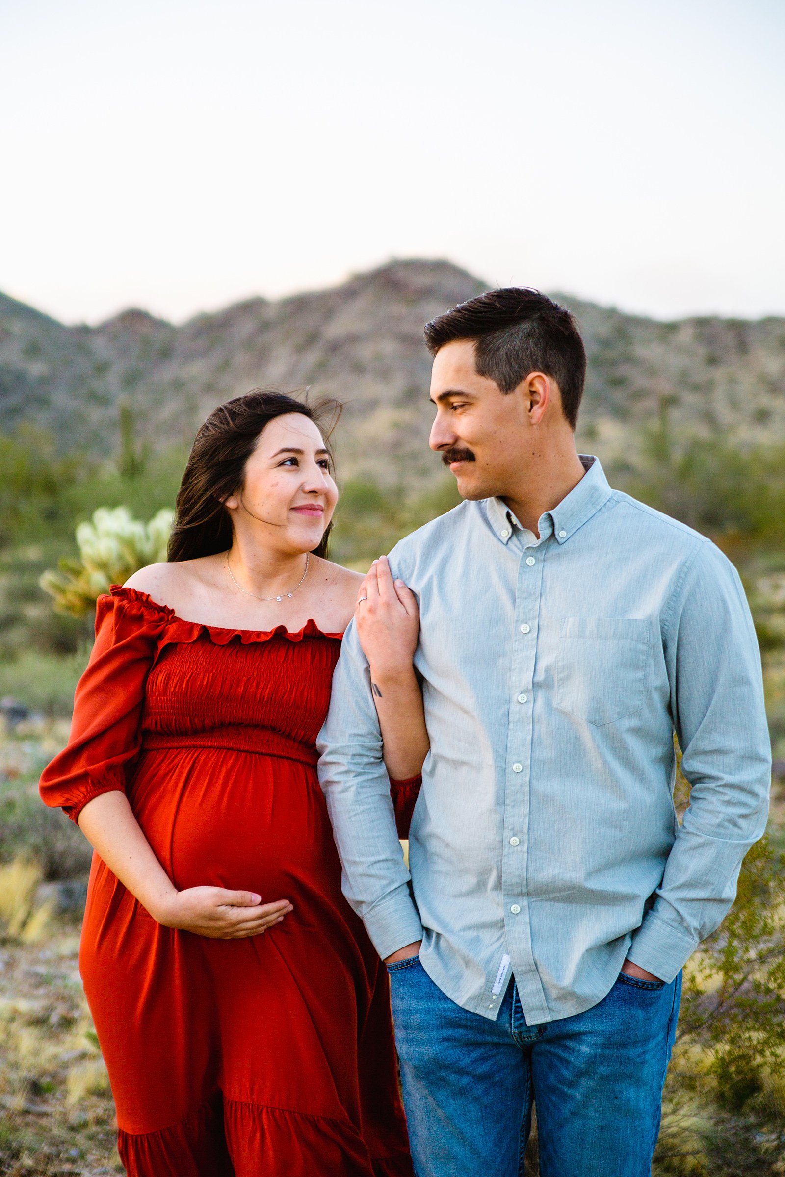 Couple look at each other during their White Tanks maternity session by Phoenix wedding photographer PMA Photography.