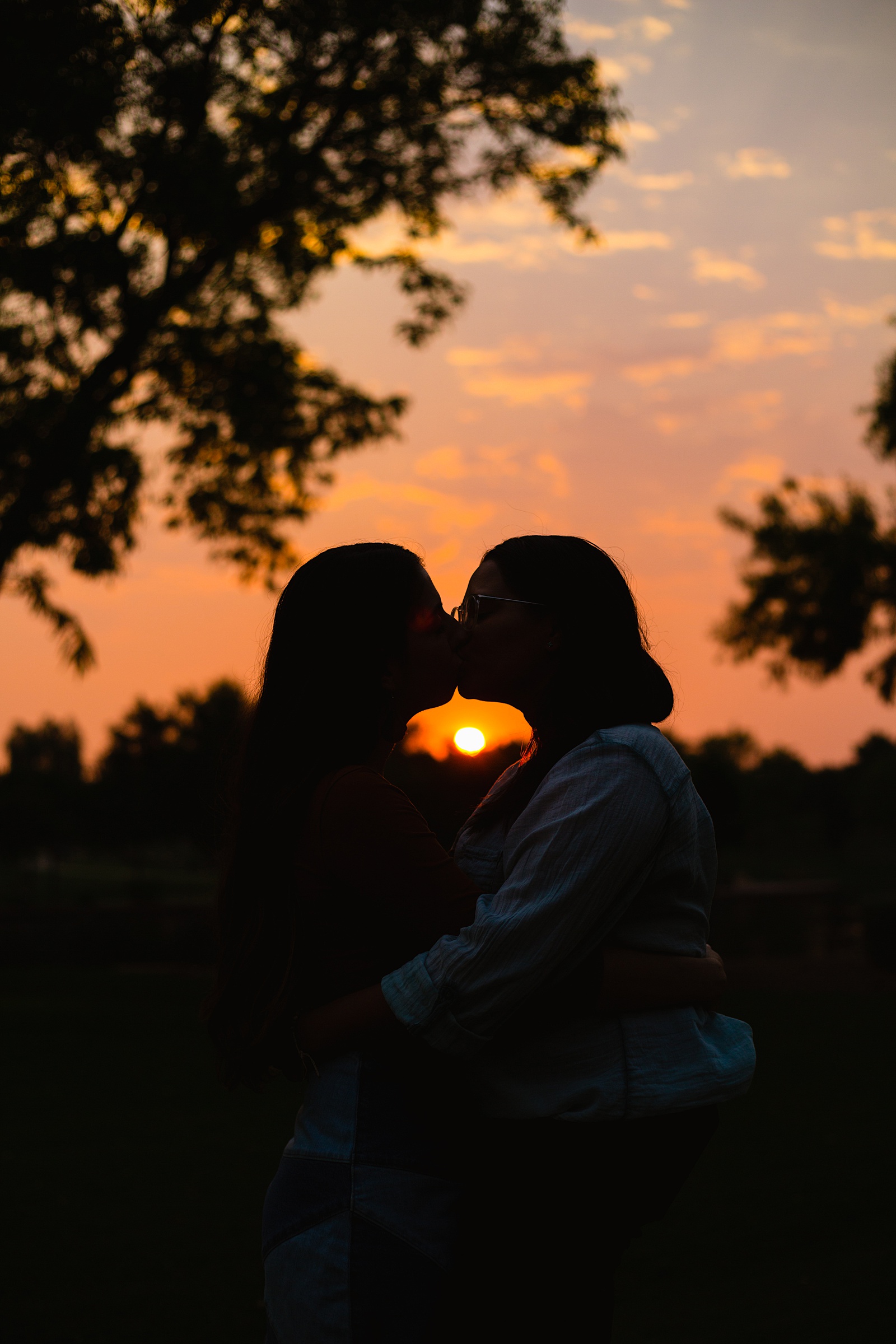 Same sex couple share a kiss at sunset during their Phoenix engagement session by Arizona wedding photographer PMA Photography.
