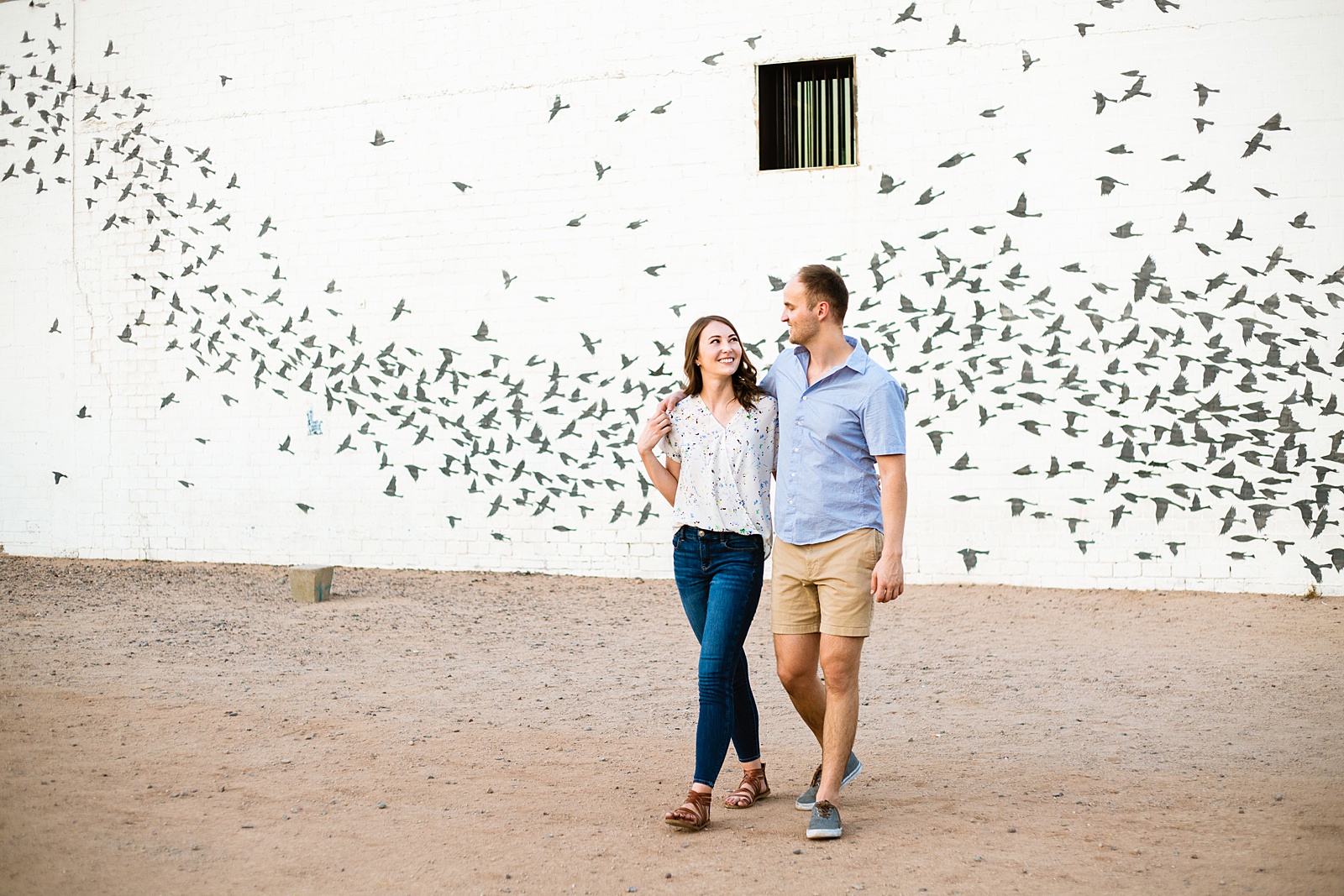 Couple walking together during their Roosevelt Row engagement session by Phoenix engagement photographer PMA Photography.