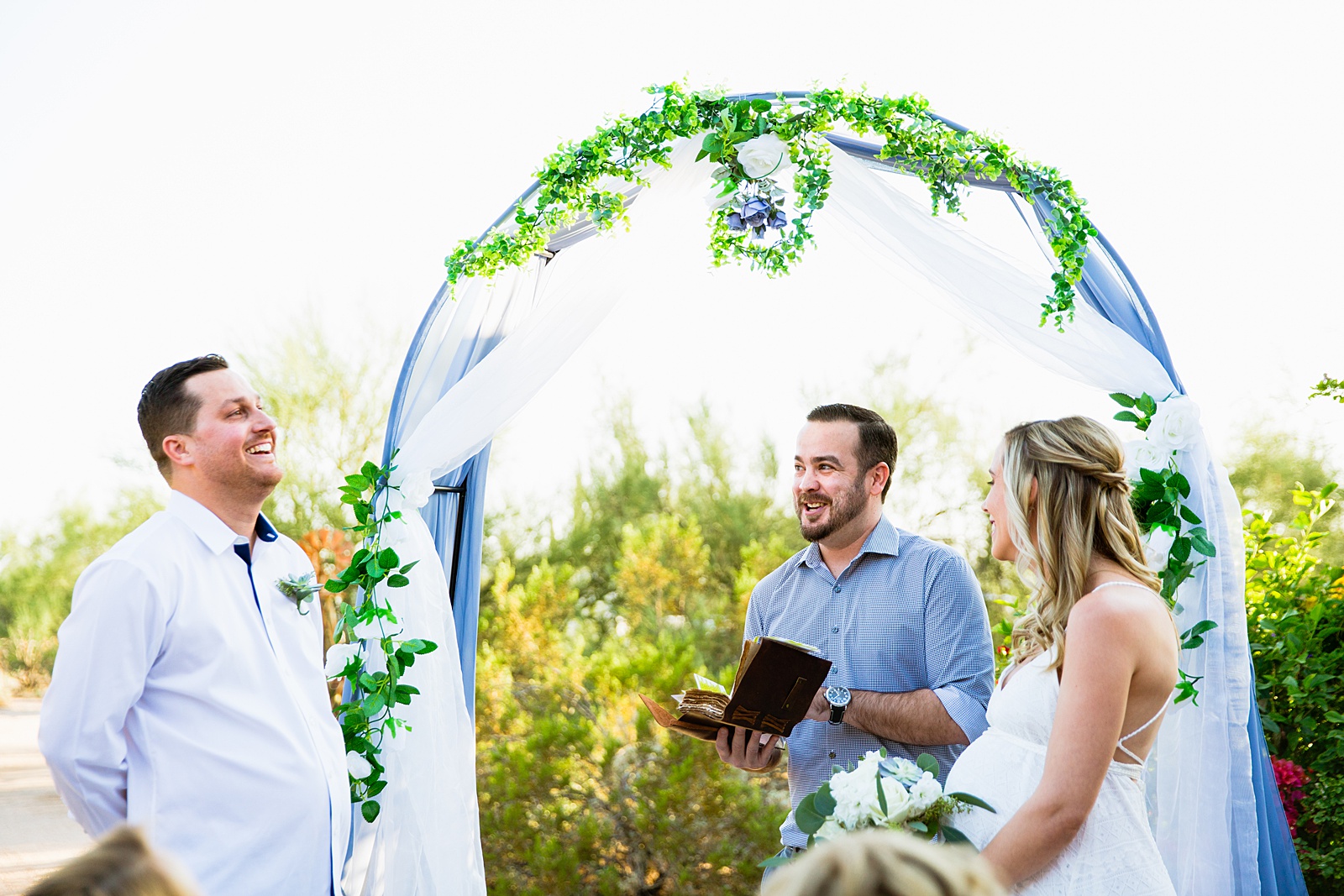 Bride and groom laughing together during their backyard garden elopement by Arizona wedding photographer PMA Photography.