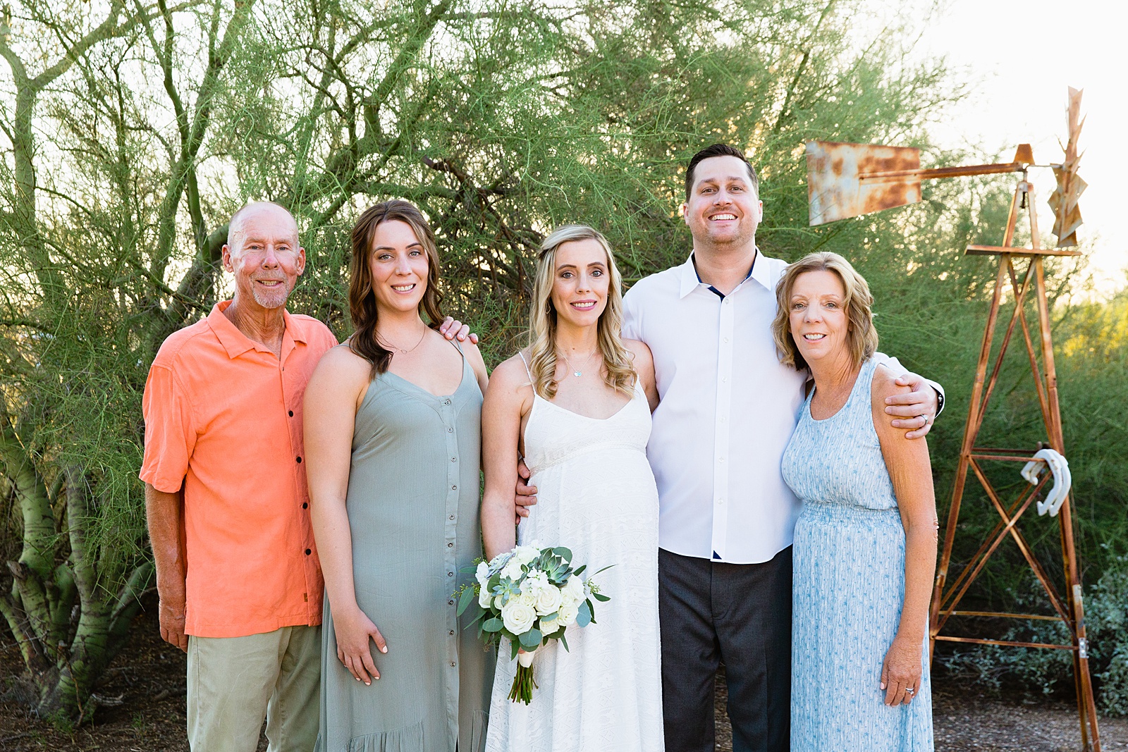 Bride and groom pose with their family members during their desert backyard elopement by Scottsdale wedding photographer PMA Photography.