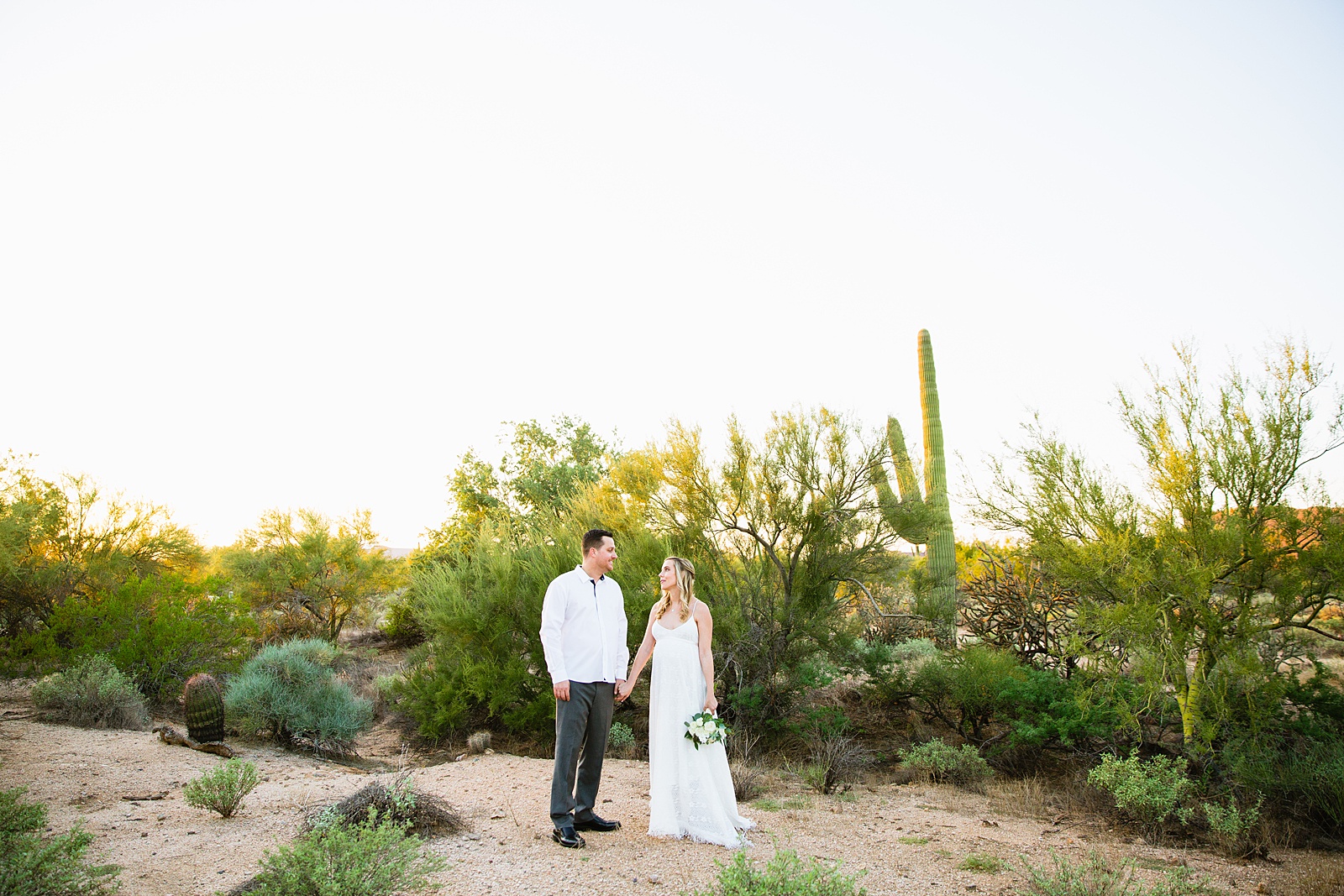 Pregnant bride and Groom pose together during their desert backyard elopement in Scottsdale by Arizona wedding photographer PMA Photography.