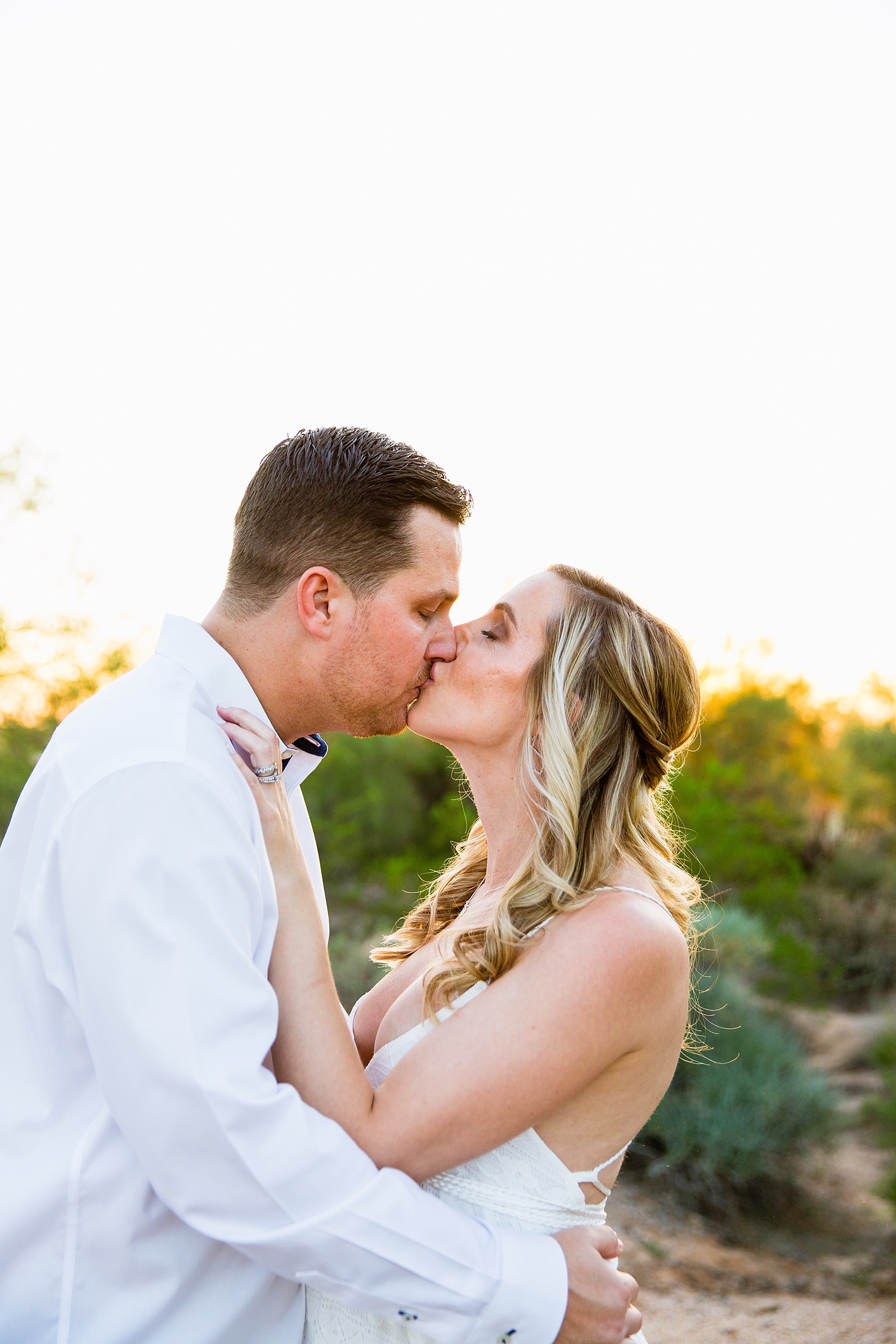 Pregnant bride and Groom share a kiss during their desert backyard elopement in Scottsdale by Arizona wedding photographer PMA Photography.