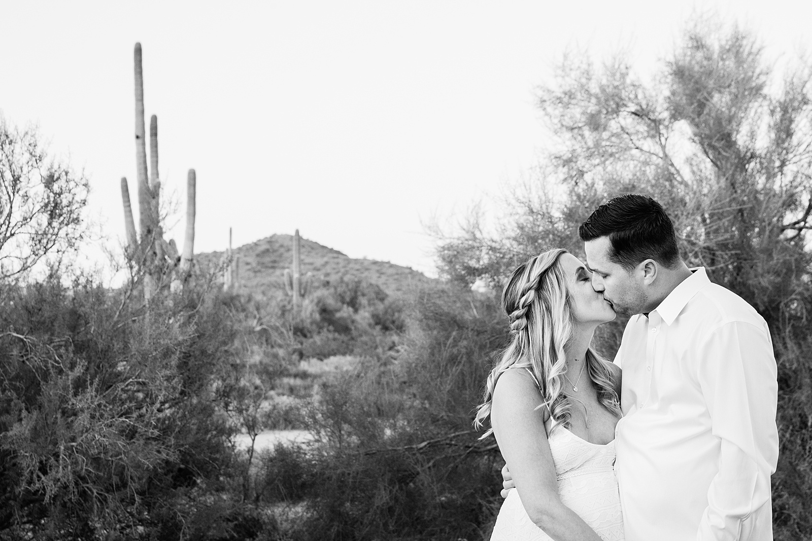 Pregnant bride and Groom share a kiss during their desert backyard elopement in Scottsdale by Arizona wedding photographer PMA Photography.