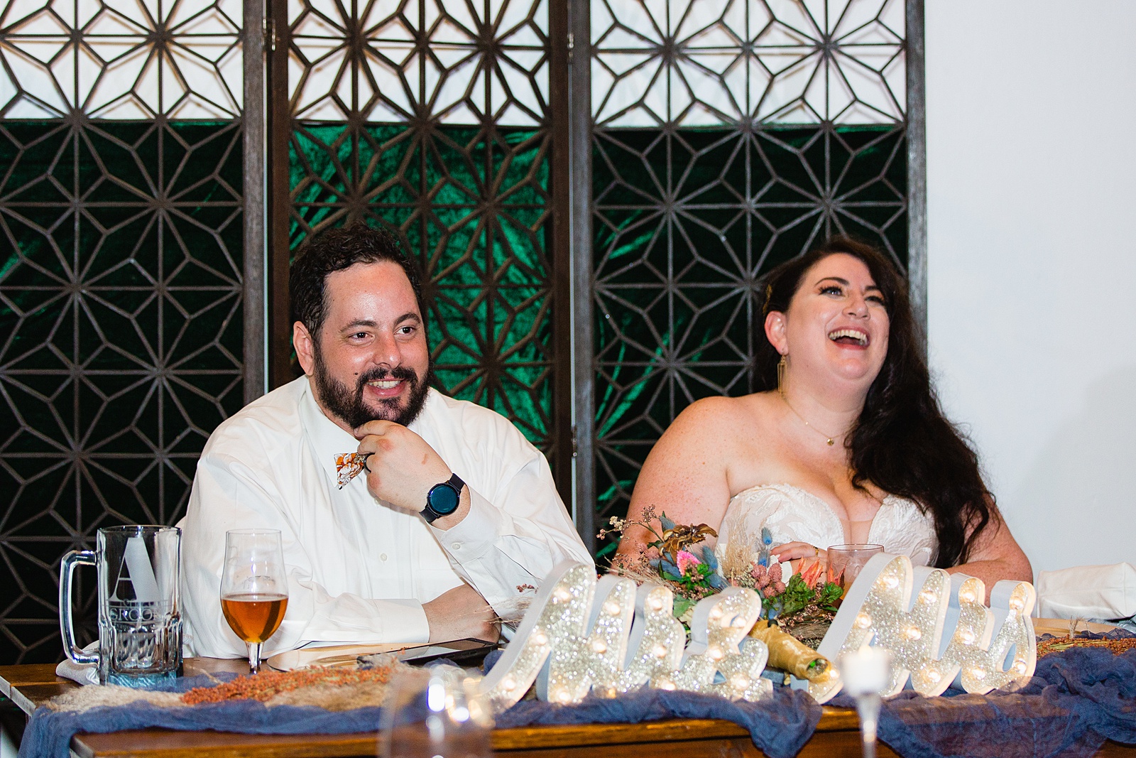 Newlyweds laughing during toast at their MoOrchid wedding reception by Phoenix wedding photographer PMA Photography.