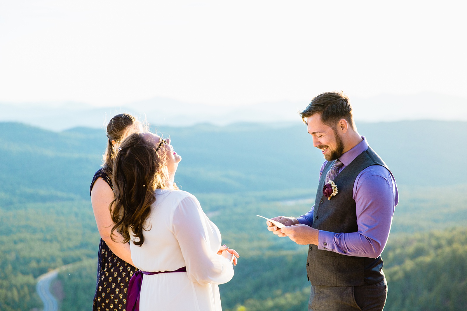 Groom reading vows while the bride laughs during their wedding ceremony at Mogollon Rim by Payson elopement photographer PMA Photography.