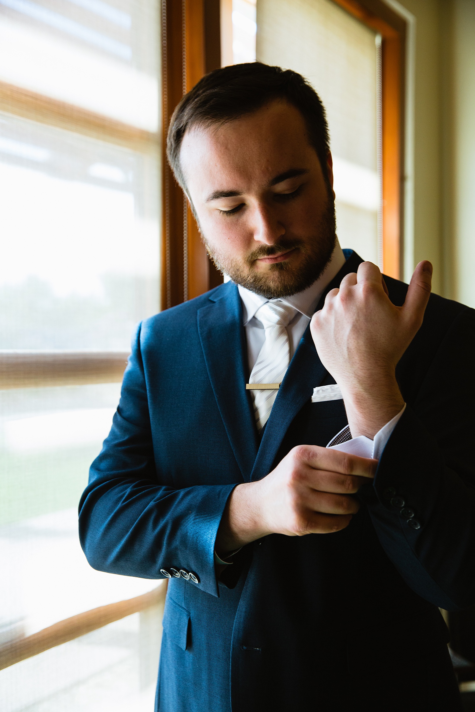 Groom adjusting his cufflinks while getting ready for his wedding by Phoenix wedding photographers PMA Photography.