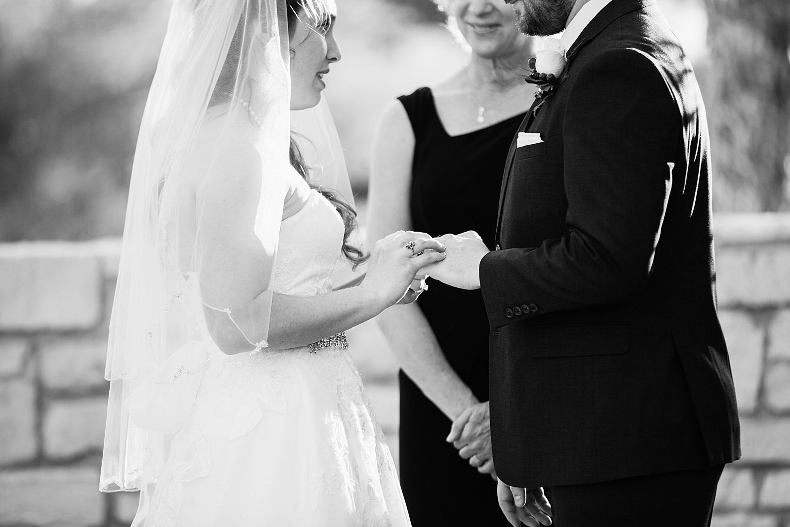 Bride and Groom exchange rings during their wedding ceremony at Ocotillo Oasis by Phoenix wedding photographer PMA Photography.