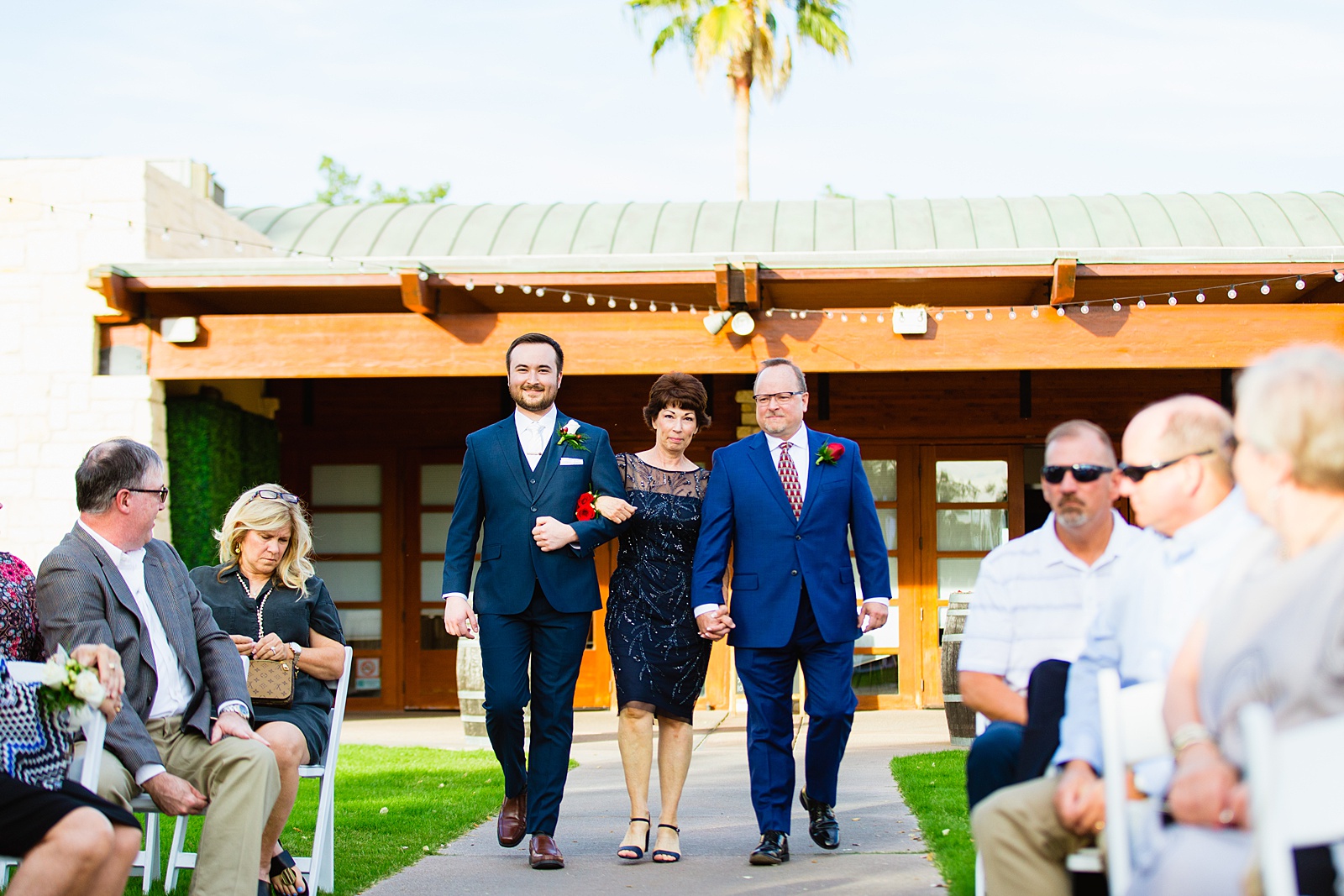 Groom walking down the aisle with his parents during Ocotillo Oasis wedding ceremony by Phoenix wedding photographer PMA Photography.