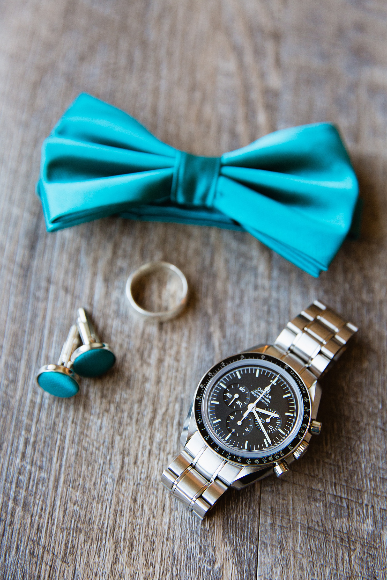 Groom's teal and silver wedding day details with a bowtie, cufflinks, and watch by Arizona wedding photographer PMA Photography.
