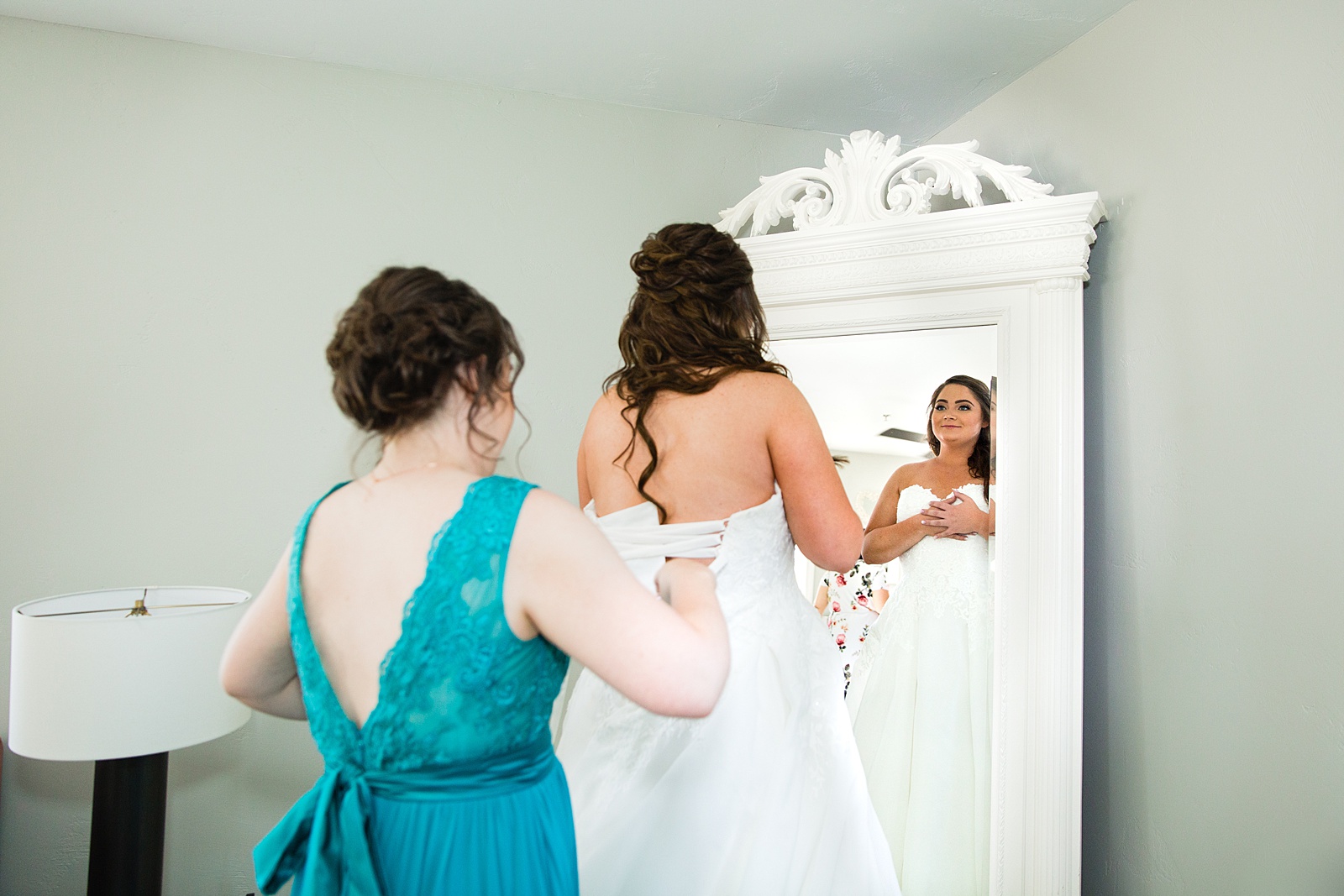 Bridesmaid helping the bride into her wedding dress by Arizona wedding photographer PMA Photography.