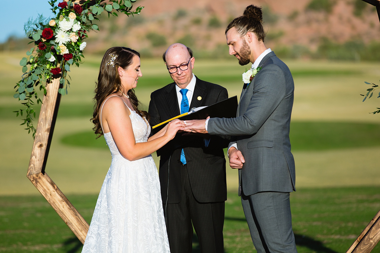 Bride and groom exchange rings during their wedding ceremony at Papago Events by Phoenix wedding photographer PMA Photography.