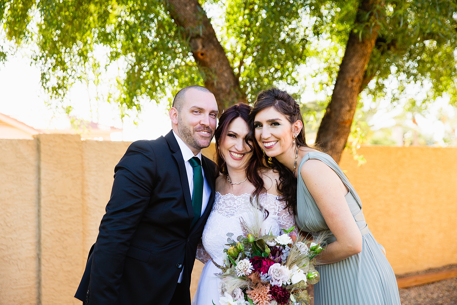 Bride and mixed gender bridal party laughing together at a Backyard Micro wedding by Arizona wedding photographer PMA Photography.