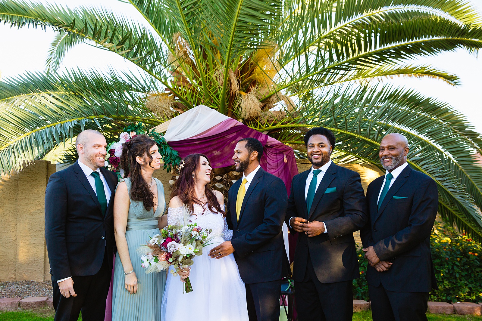 Mixed gender bridal party laughing together at Backyard Micro wedding by Scottsdale wedding photographer PMA Photography.