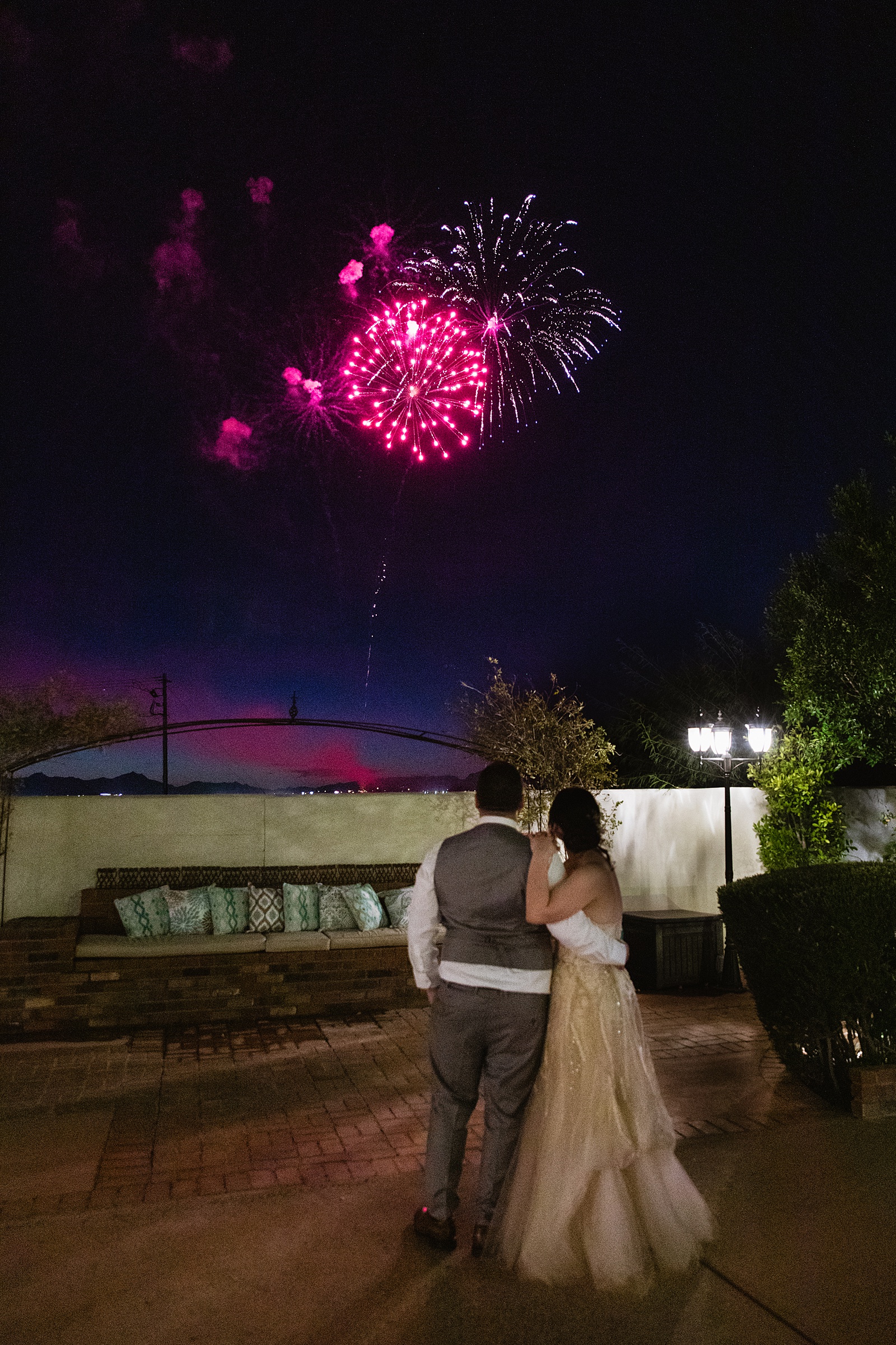 Bride and Groom together while fireworks go off in the sky during their Bella Rose Estate wedding by Arizona wedding photographer PMA Photography.