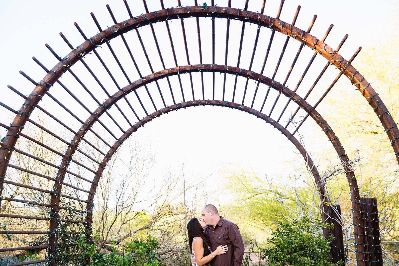 Couple share a kiss during their Desert Botanical Garden engagement session by Phoenix wedding photographer PMA Photography.