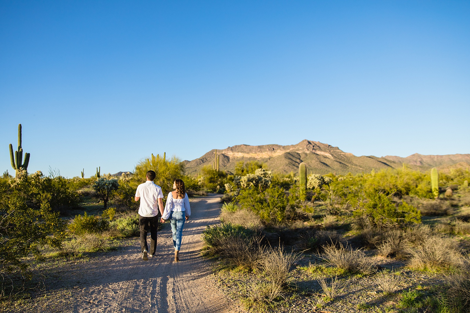 Couple walking together during their Phoenix engagement session by Arizona engagement photographer PMA Photography.