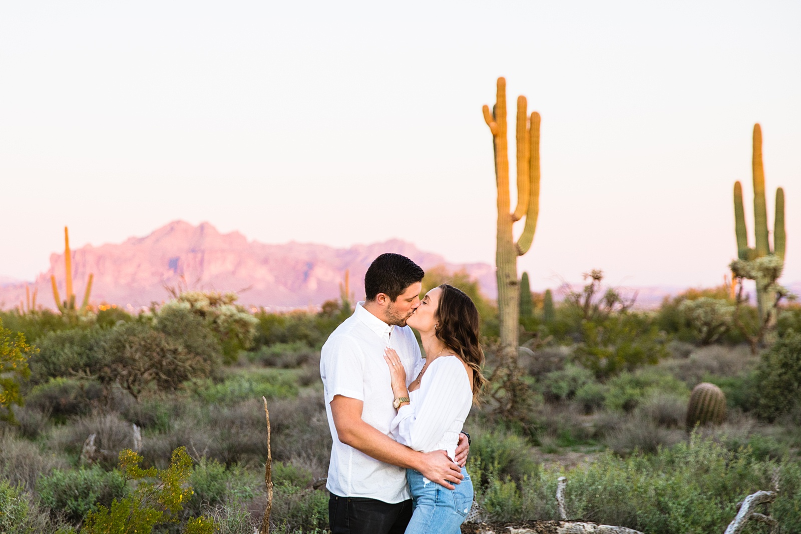 Couple share a kiss during their desert engagement session by Phoenix wedding photographer PMA Photography.