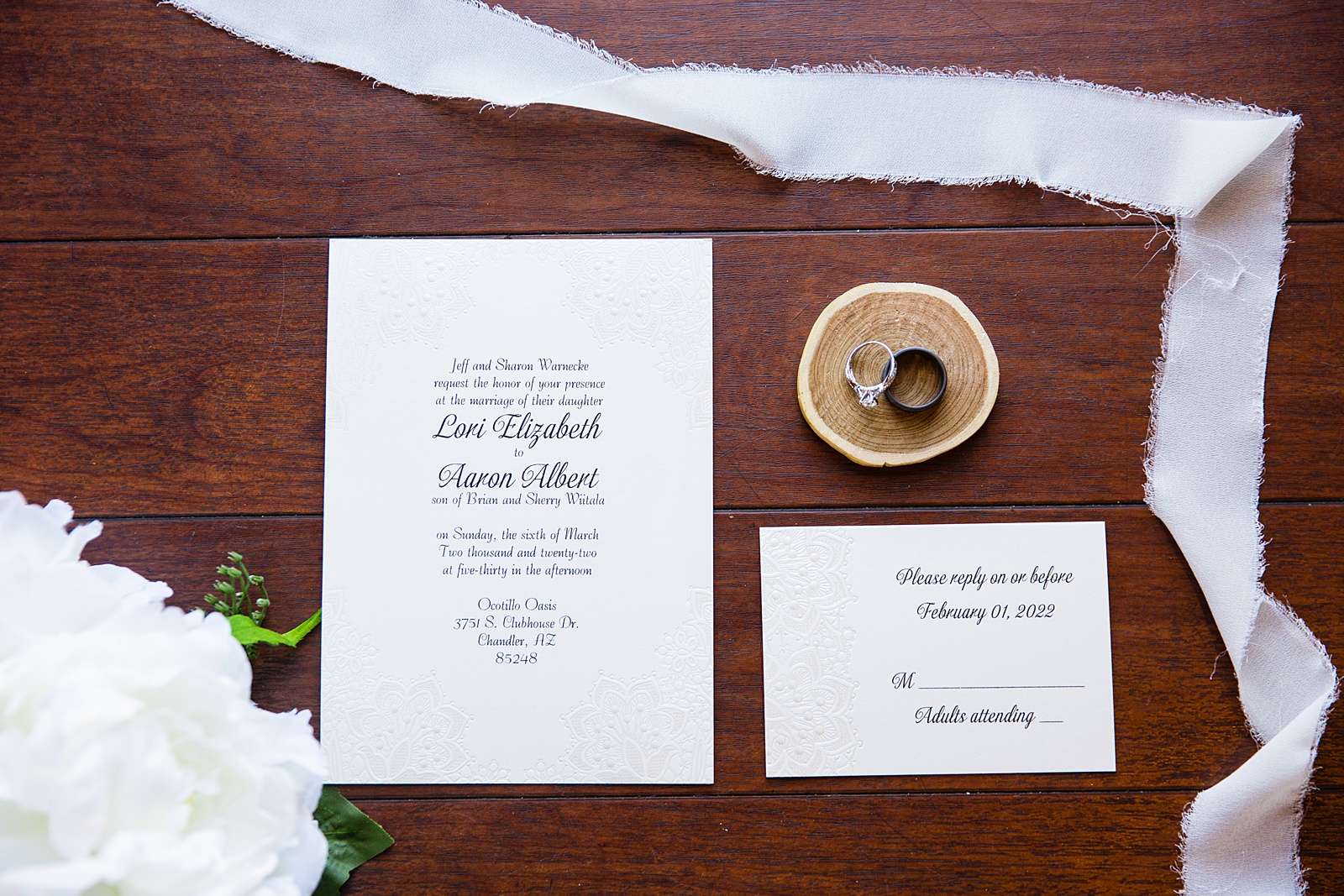 Bride and grooms wedding rings on top of classic wedding invitations by PMA Photography.