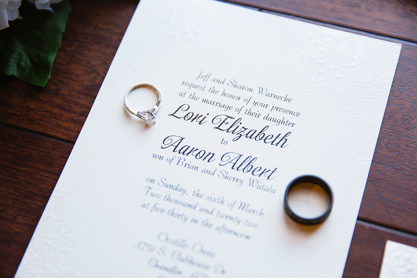 Bride and grooms wedding rings on top of classic wedding invitations by PMA Photography.
