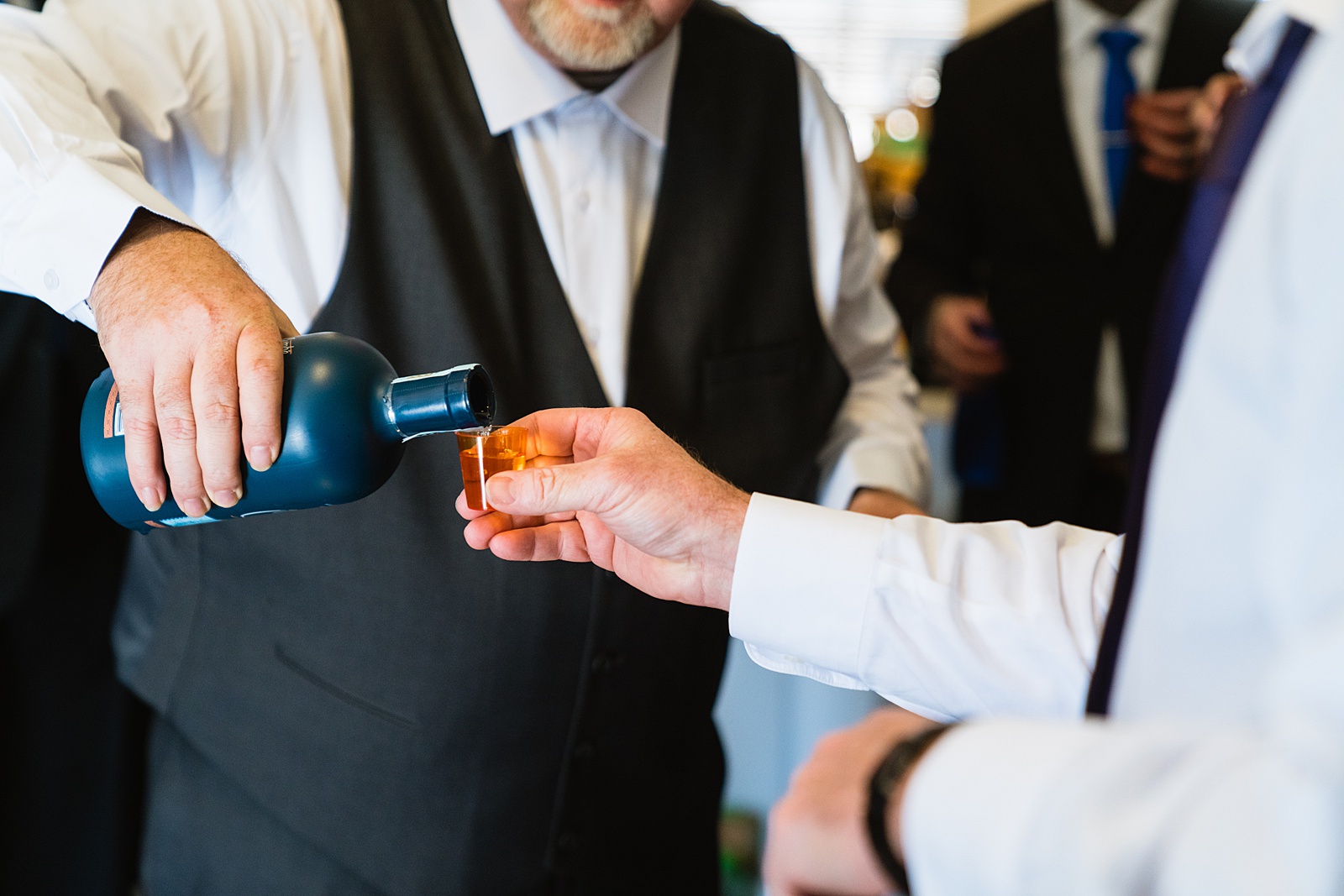Groom toasting with groomsmen on his wedding day by PMA Photography.