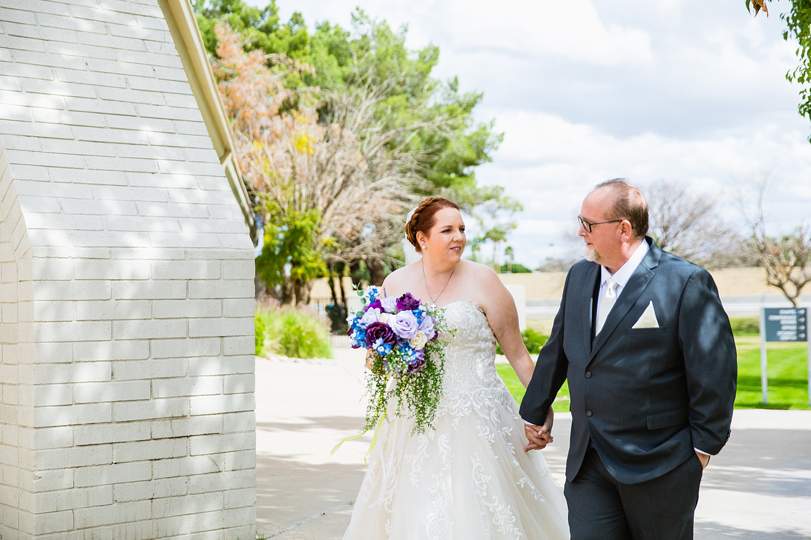Bride and groom walking together during their Sun Valley Church wedding by Arizona wedding photographer PMA Photography.