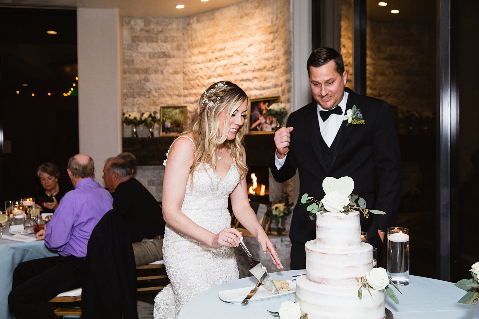 Newlyweds cutting their wedding cake at their Troon North wedding reception by Arizona wedding photographer PMA Photography.