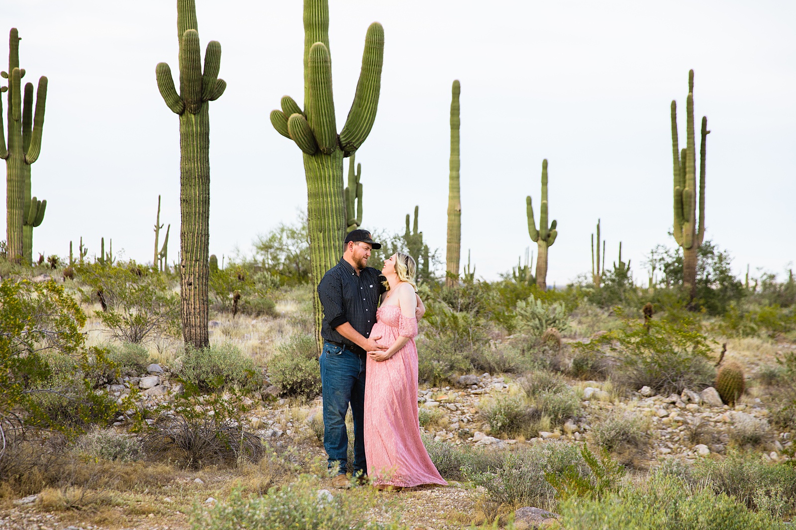 Couple look at each other during their White Tanks Desert maternity session by Phoenix maternity photographer PMA Photography.