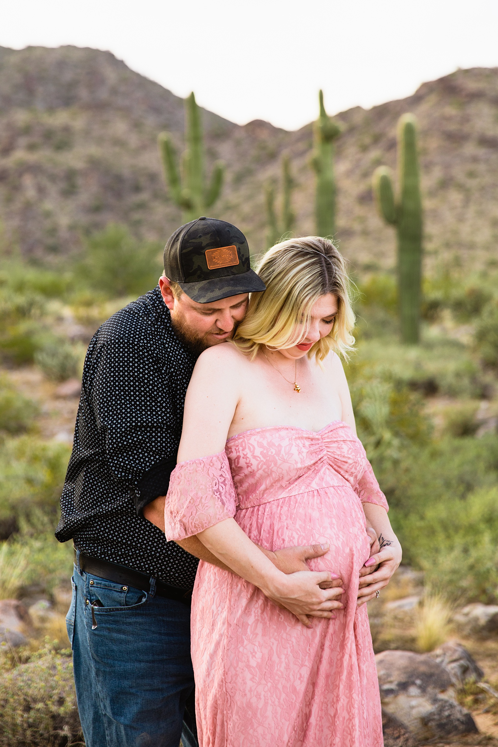 Couple look at their pregnant belly during their White Tanks Desert maternity session by Phoenix maternity photographer PMA Photography.