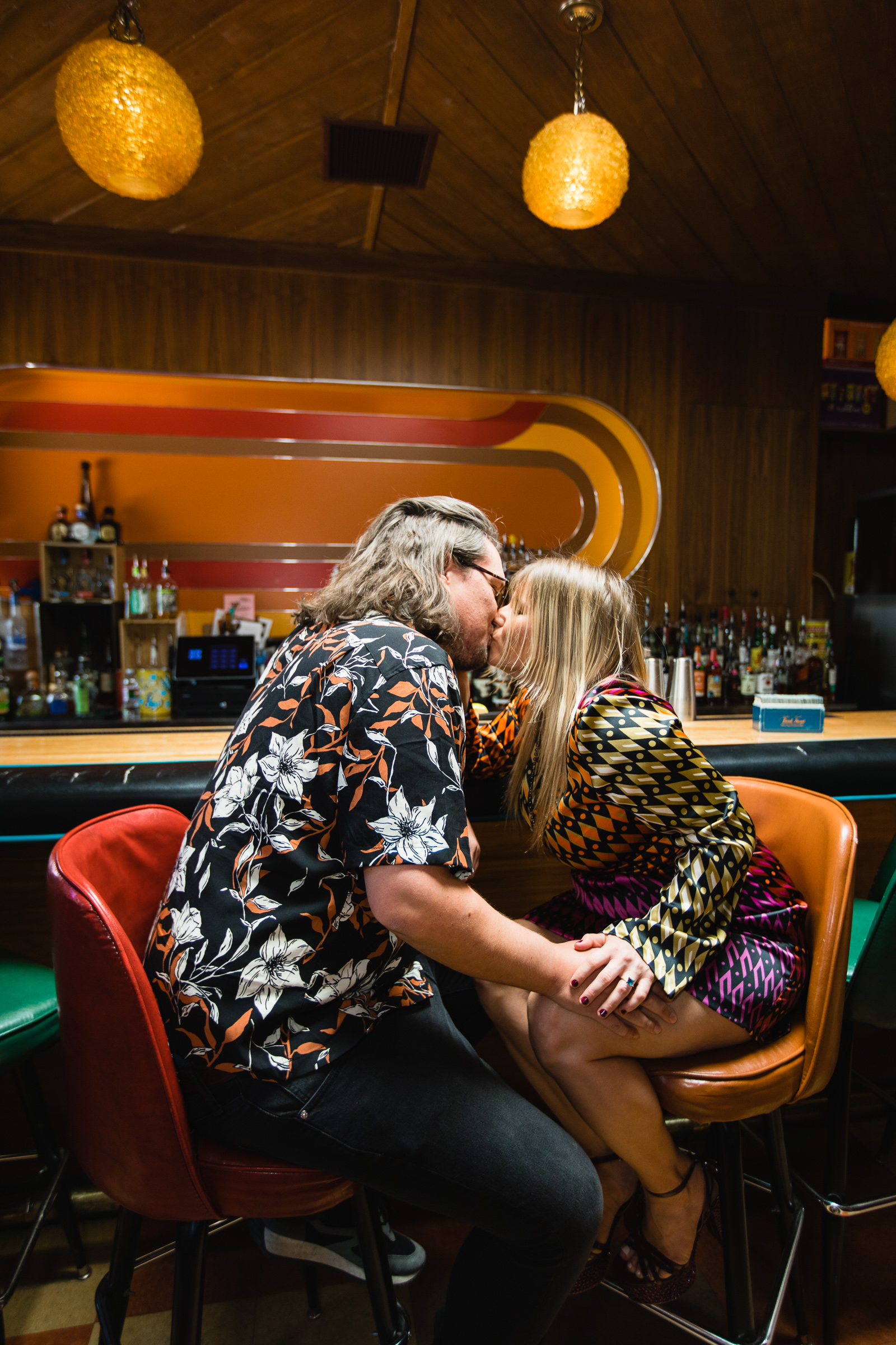 Couple sharing drinks together at the bar during their Thunderbird Lounge engagement session by Phoenix wedding photographer PMA Photography.