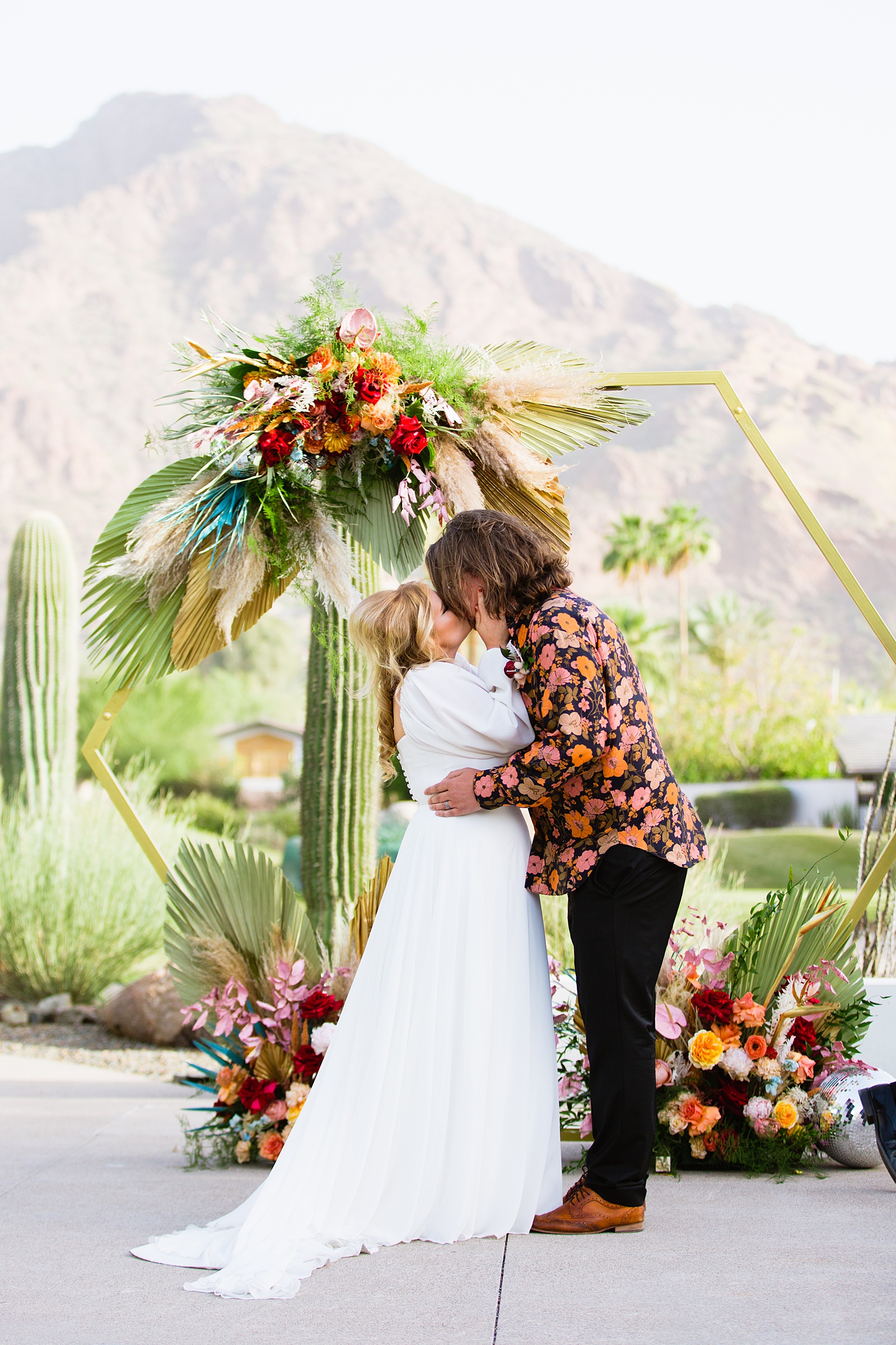 Bride and groom share their first kiss during their wedding ceremony at Mountain Shadows Resort by Arizona wedding photographer PMA Photography.