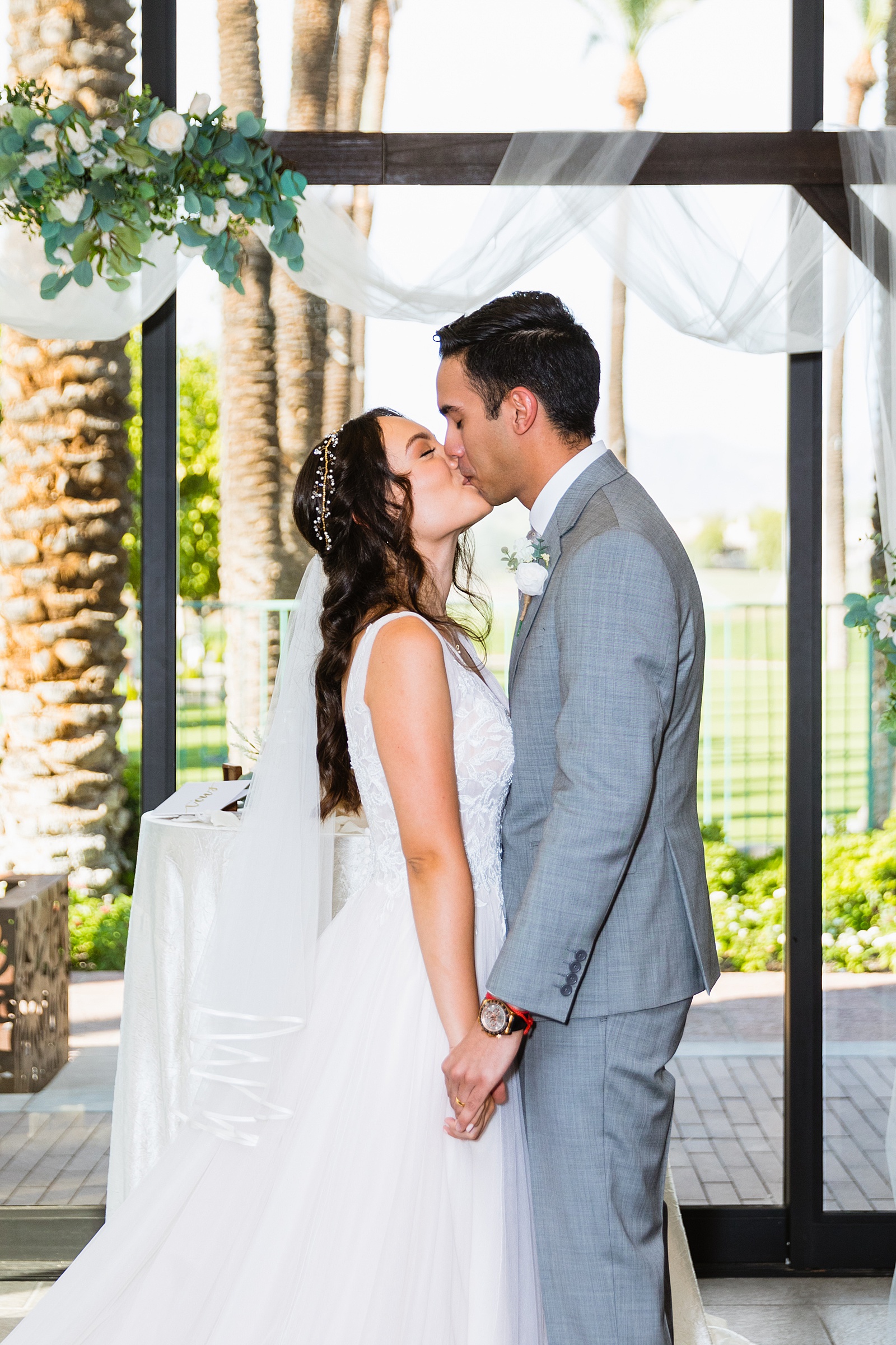 Bride and groom share their first kiss during their wedding ceremony at Hyatt Regency Scottsdale Resort & Spa At Gainey Ranch by Arizona wedding photographer PMA Photography.