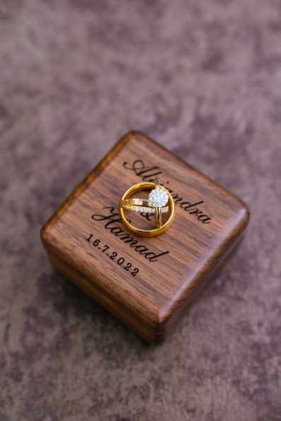 Couple's gold wedding rings on their custom ring box by PMA Photography.