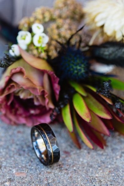 Brides's wedding day details of unique black wedding band with boutonniere by PMA Photography.