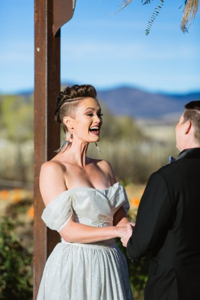 Same sex couple laughing togethering during Mortimer Farms wedding ceremony by Prescott wedding photographer PMA Photography.