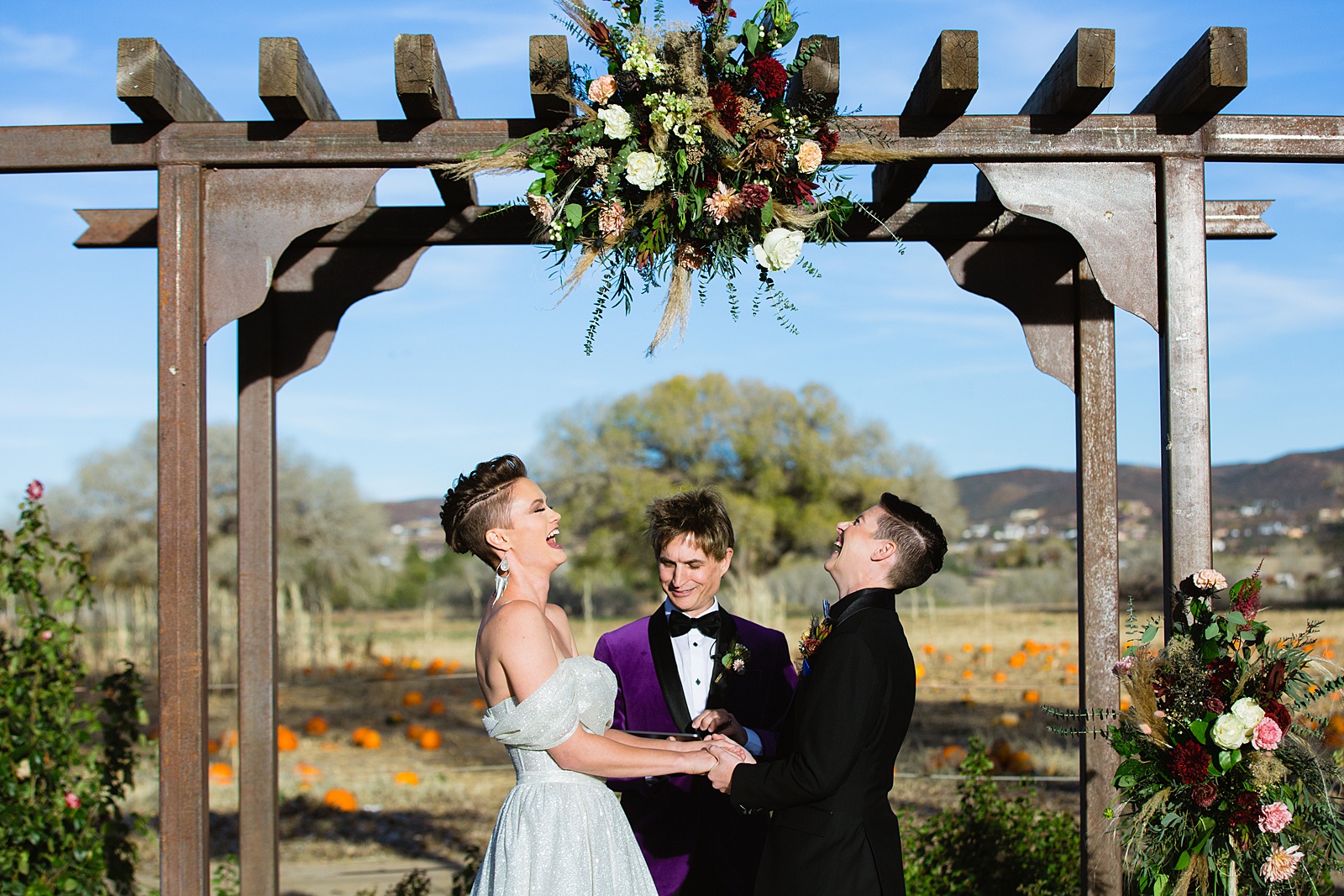Same sex couple laughing together during their wedding ceremony at Mortimer Farms by Phoenix wedding photographer PMA Photography.
