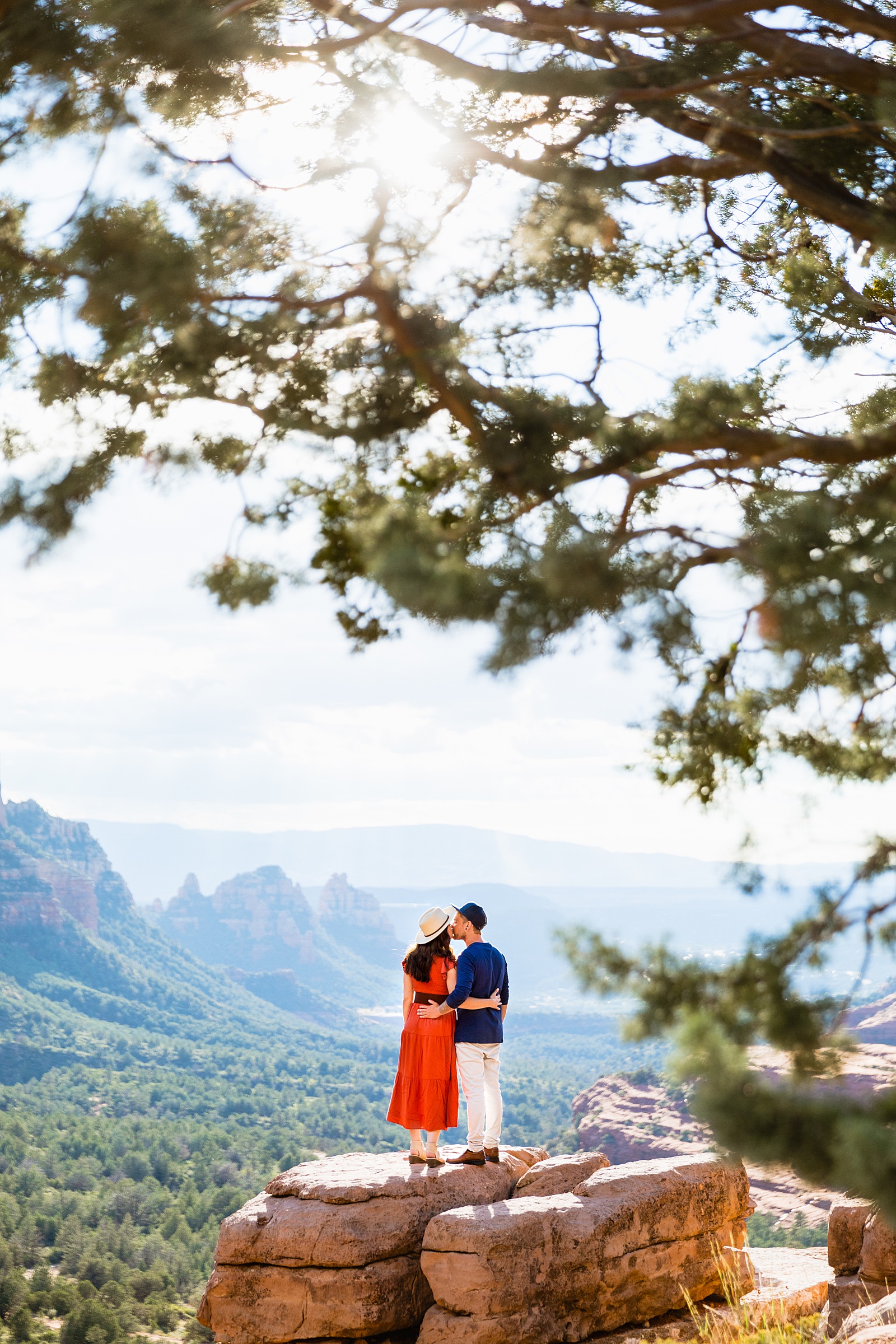 Adventurous couple share a kiss during their Sedona engagement session by Arizona wedding photographer PMA Photography.