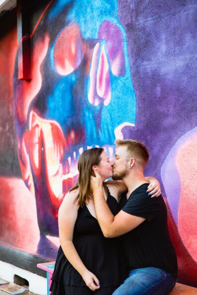 Couple share a kiss during their Roosevelt Row engagement session by Phoenix wedding photographer PMA Photography.
