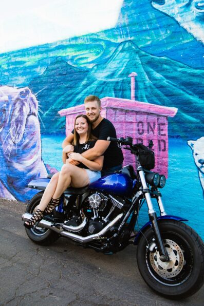 Adventurous couple pose on a motorcycle for their Roosevelt Row engagement session by Phoenix wedding photographer PMA Photography.