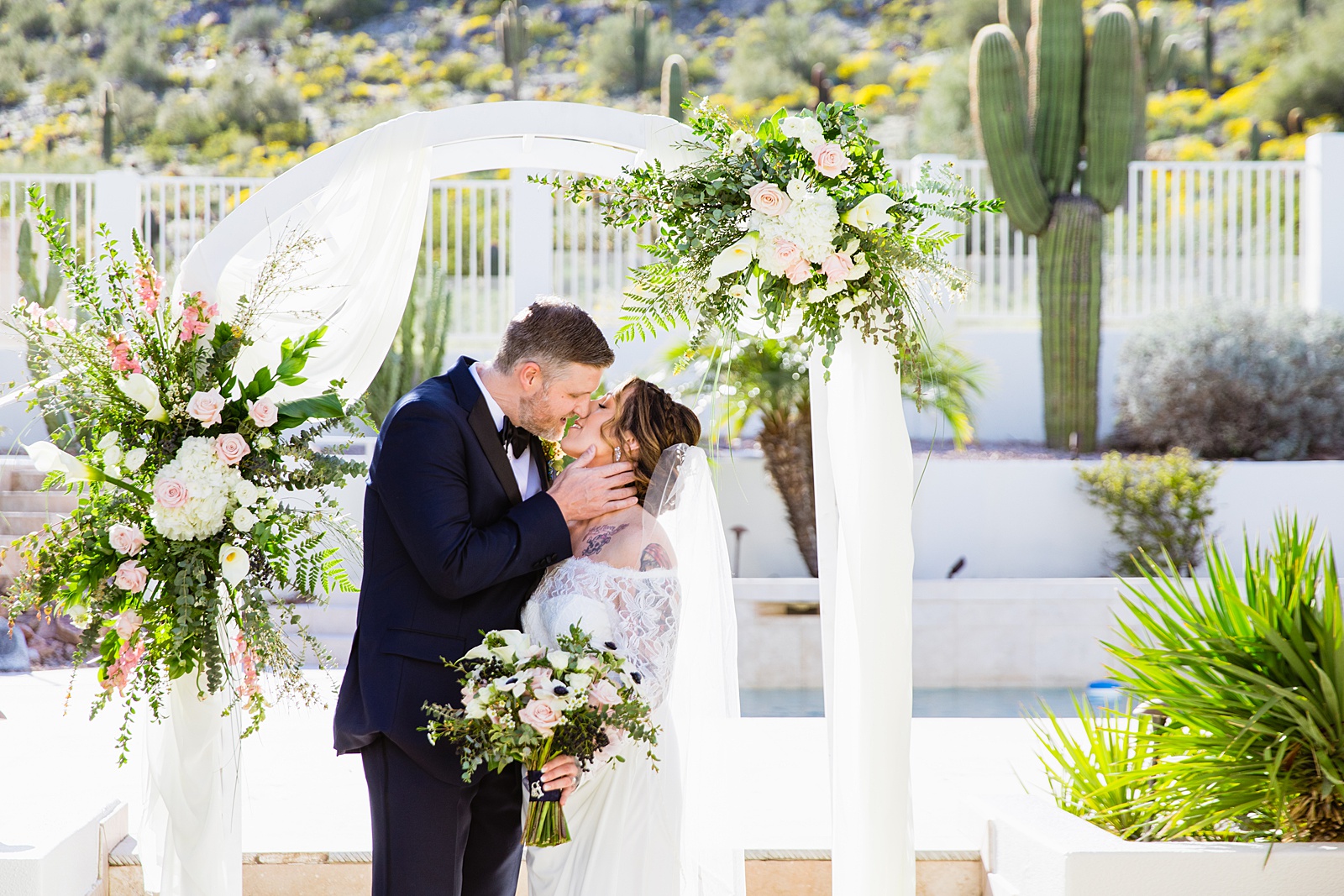 Bride and groom share a kiss during their backyard wedding by Arizona wedding photographer PMA Photography.