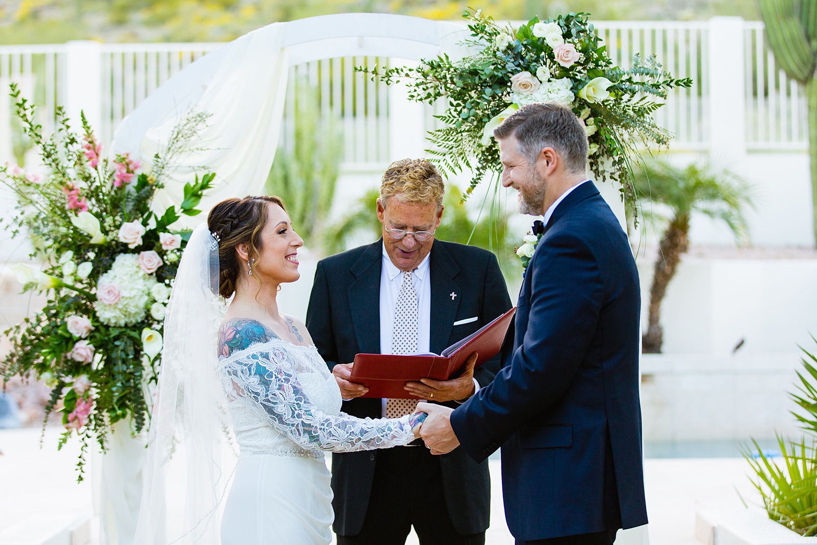 Bride and groom exchange vows during their backyard wedding ceremony by Scottsdale wedding photographer PMA Photography.