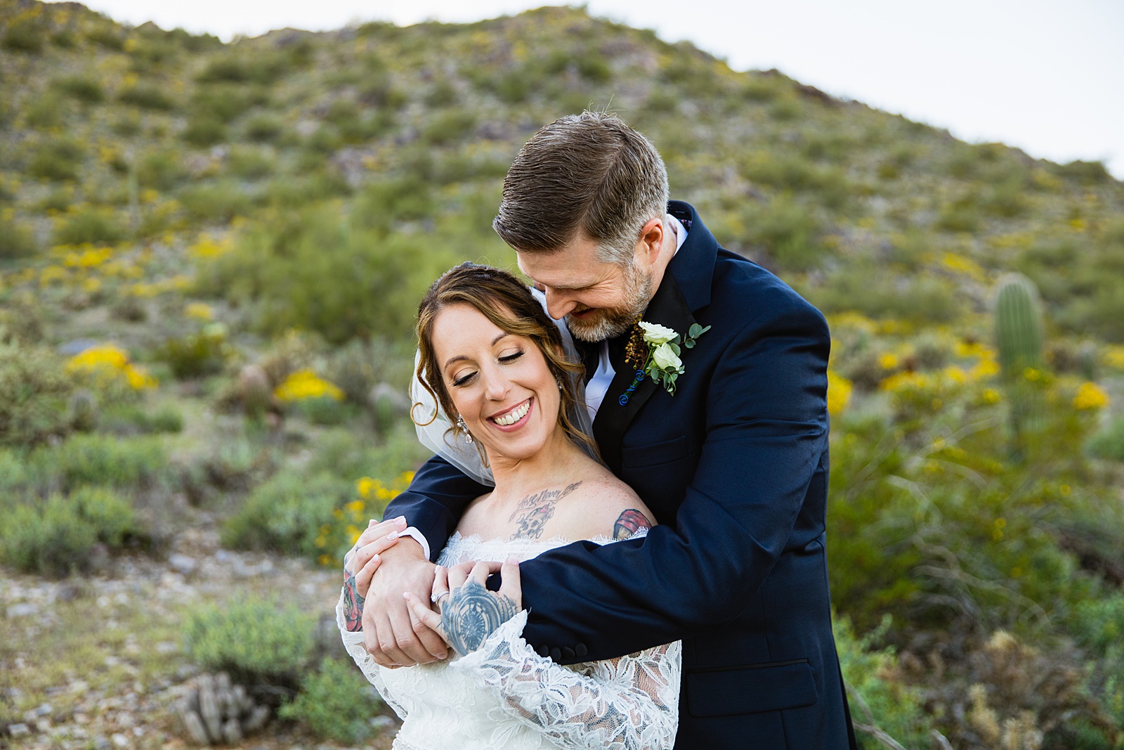 Bride and groom laughing together during their backyard wedding by Scottsdale wedding photographer PMA Photography.
