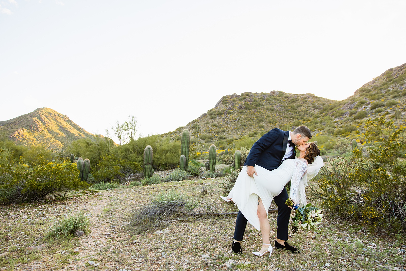 Bride and groom share a kiss during their backyard wedding by Scottsdale wedding photographer PMA Photography.