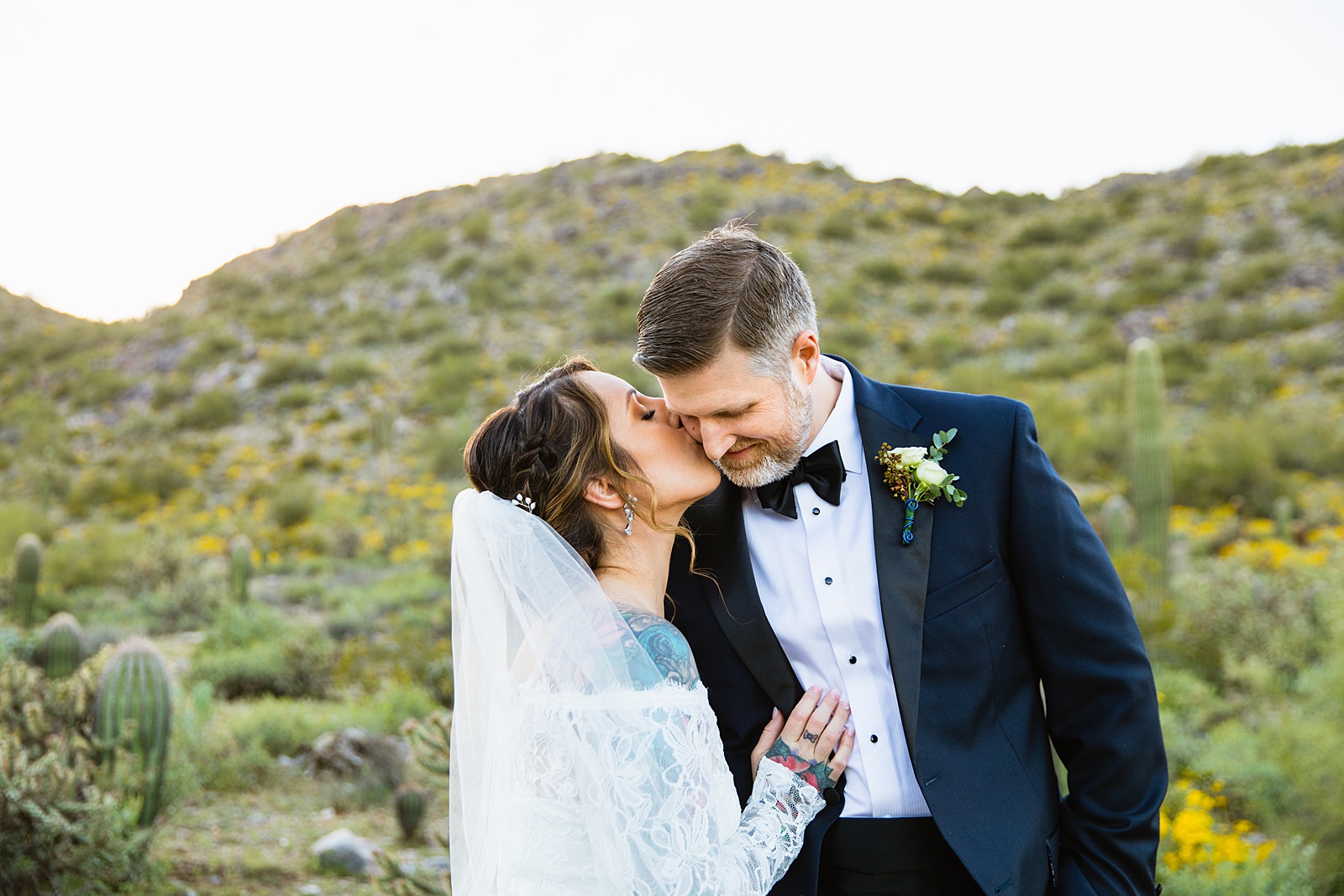 Bride and groom share a kiss during their backyard wedding by Scottsdale wedding photographer PMA Photography.