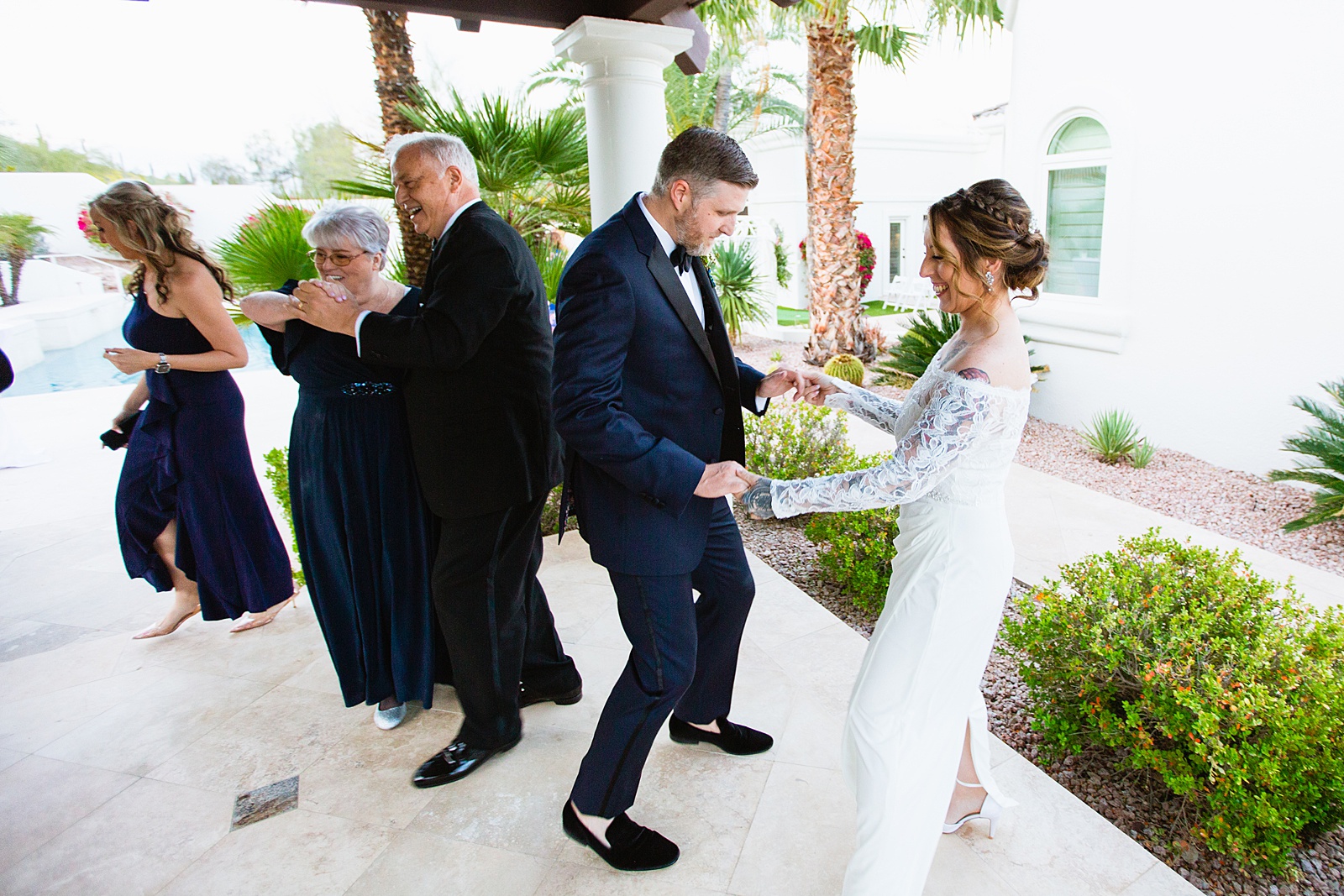 Newlyweds and guests dancing together at backyard wedding reception by Scottsdale wedding photographer PMA Photography