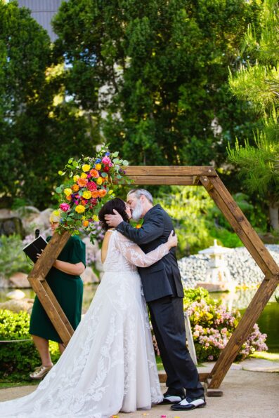 Bride and groom share their first kiss during their wedding ceremony at Japanese Friendship Garden by Arizona wedding photographer PMA Photography.