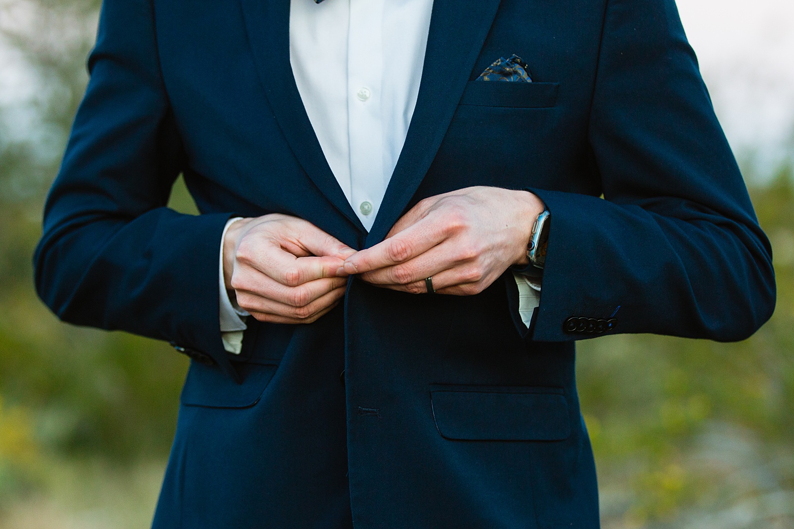 Groom buttoning his navy blue suit for his White Tanks elopement by PMA Photography.