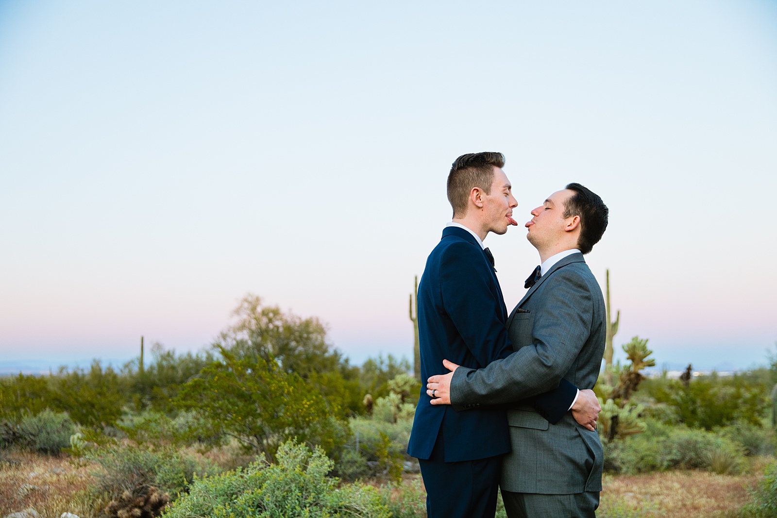LGBTQ couple sticking out their tongues at each other during their White Tanks elopement by Arizona elopement photographer PMA Photography.