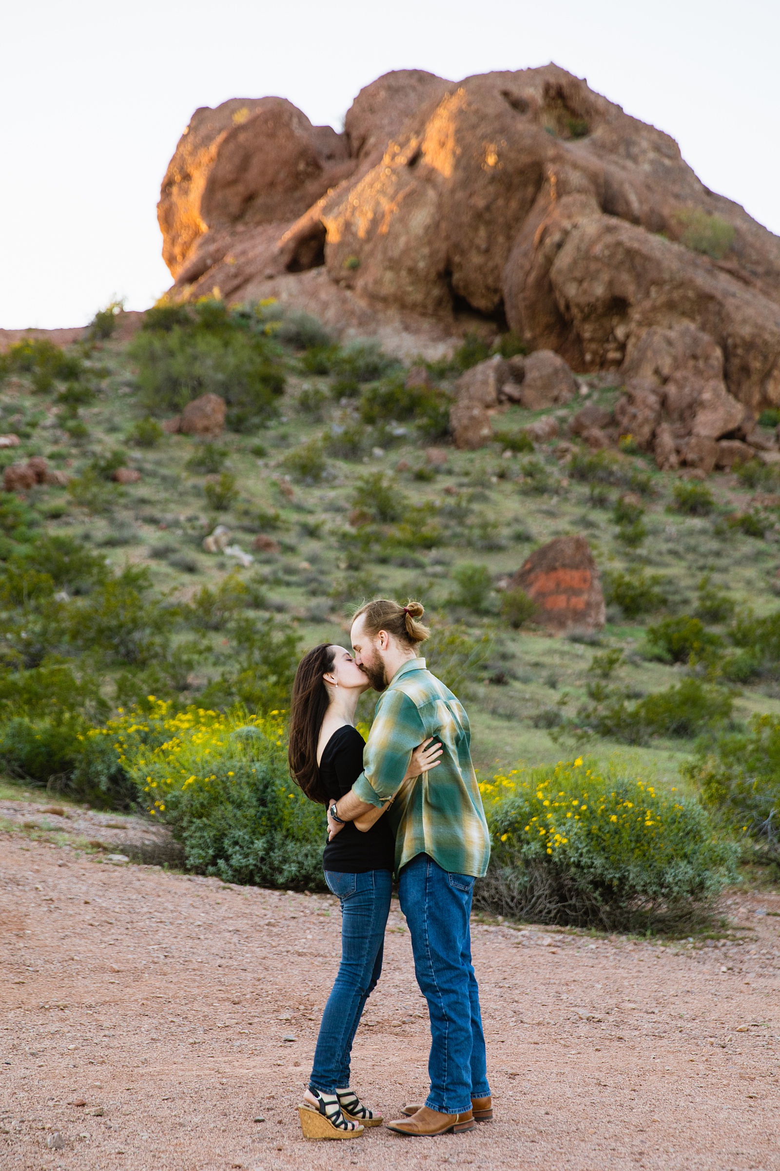Adventurous couple share a kiss during their Papago Park engagement session by Tempe wedding photographer Juniper and Co Photography.