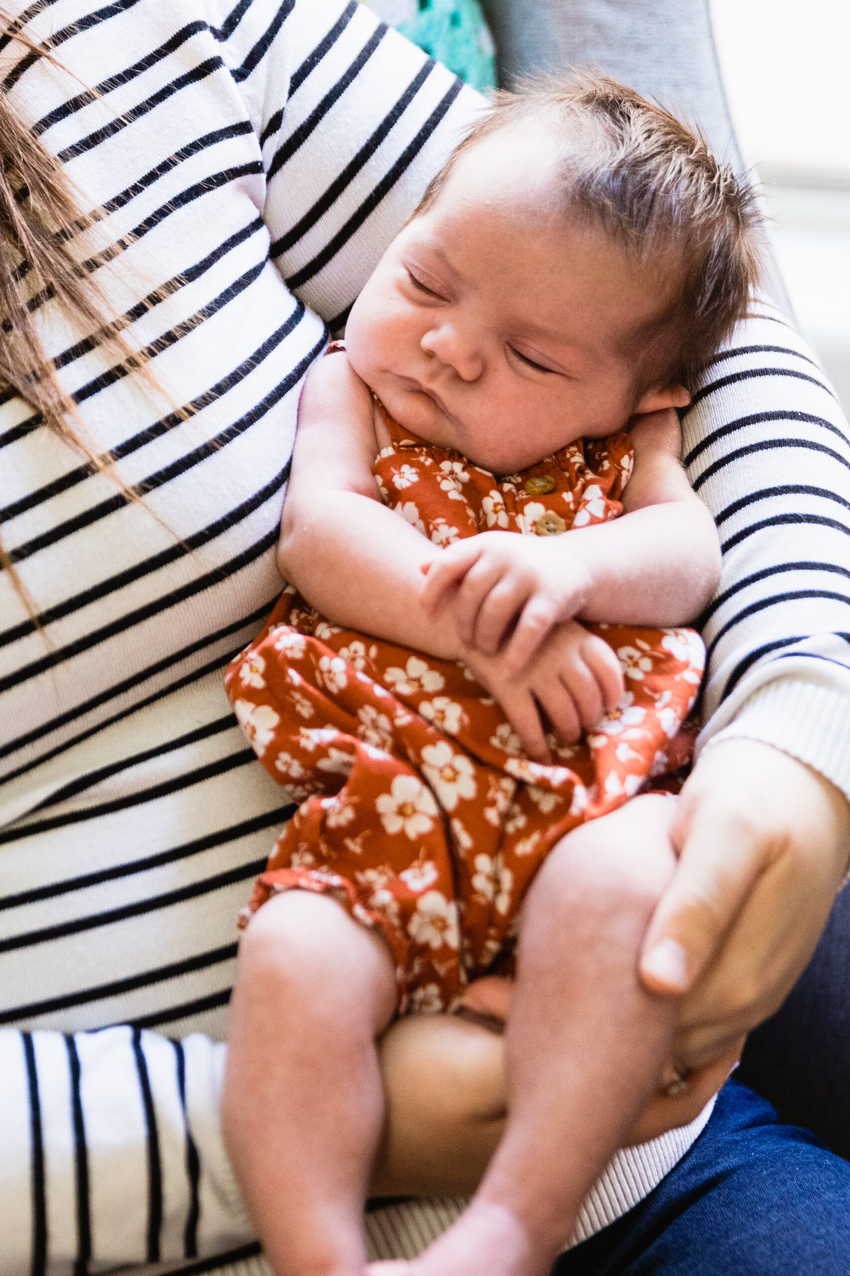 Newborn in her mother's arms during their in-home newborn Phoenix family session by Arizona family photographer Juniper and Co Photography.